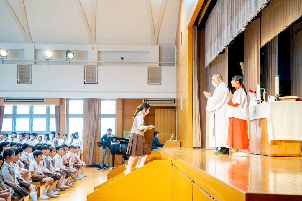 聖母月のミサ・集いにて、神父と児童の様子
